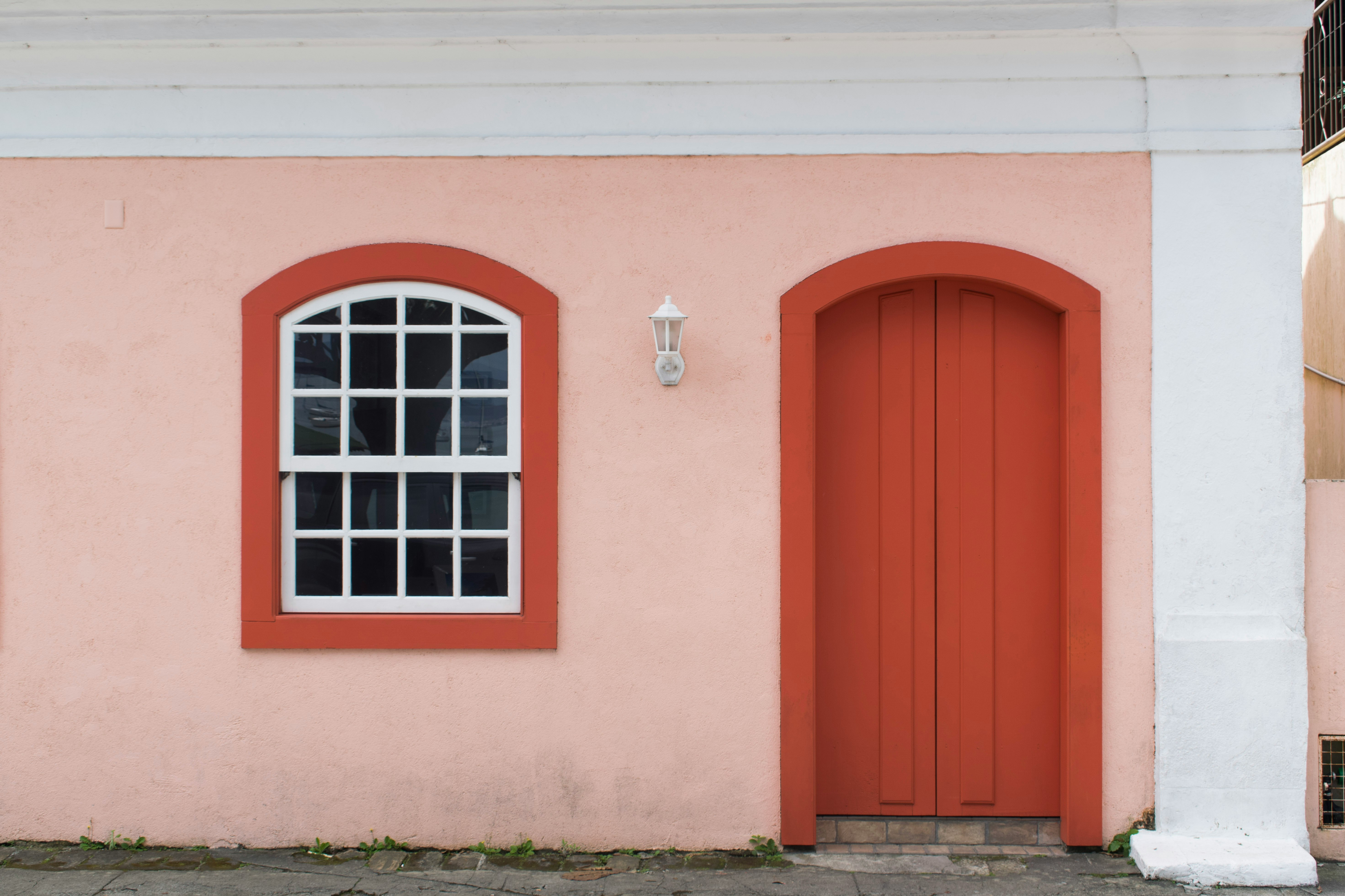 pink concrete house showing closed orange wooden door
